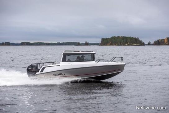 A white Falcon C7 boat speeds across a calm lake with green islands in the background under a cloudy sky.